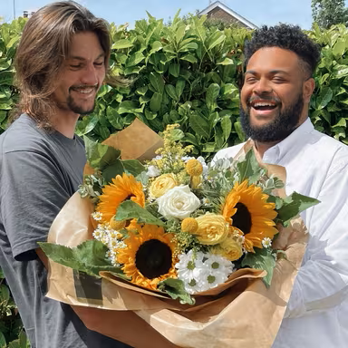 two-men-holding-bouquet-of-flowers-with-sunflowers